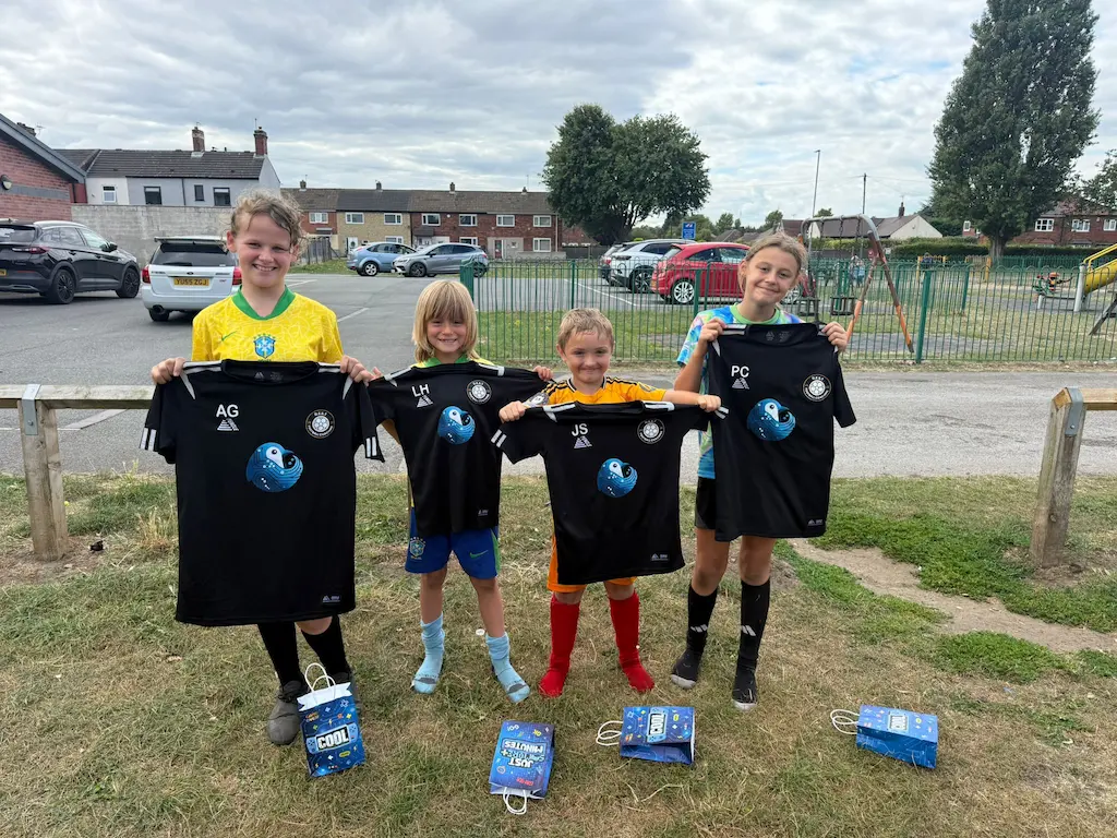 D.E.S.T Football Coaching Summer Camp 2025 - Children proudly wearing D.E.S.T football shirts with Blue Penguin Digital logo sponsorship